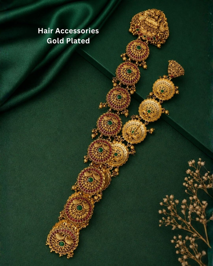 Gold-toned traditional Indian jewelry set featuring a necklace and matching earrings displayed on a black jewelry bust against a dark purple background.