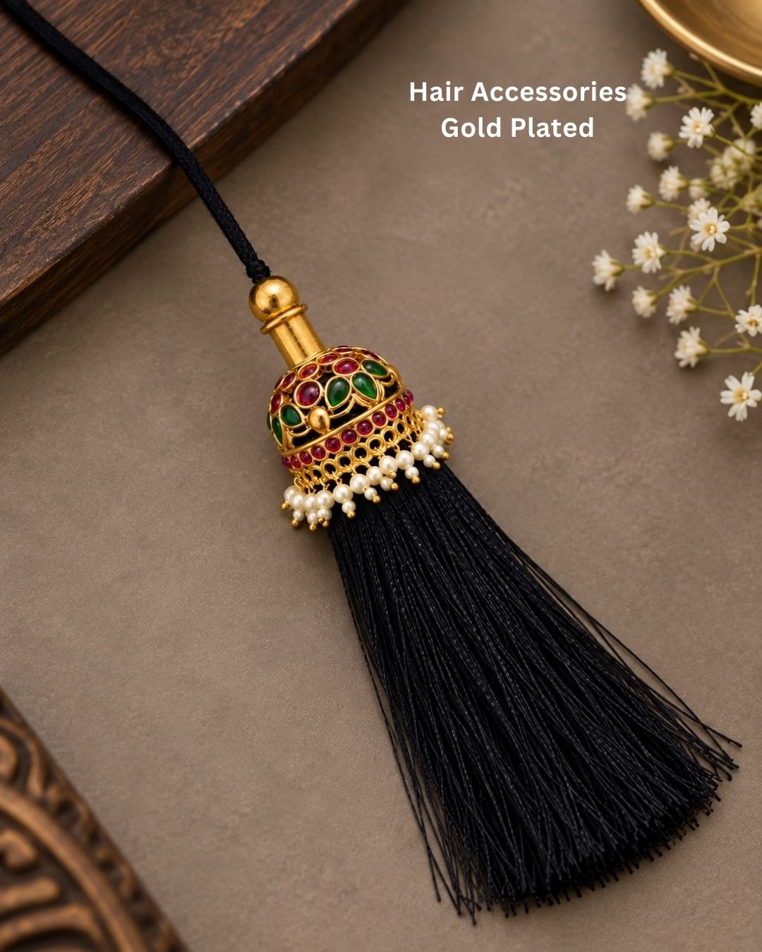 Elegant gold plated Jada Gantalu with intricate dome-shaped detailing, green and ruby stones, pearl accents, and long black thread tassels, perfect for bridal and festive hairstyles.