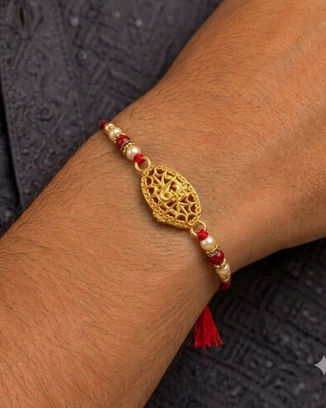 Elegant gold plated Rakhi showcasing a detailed Om symbol centerpiece with decorative pearl and red bead embellishments on a vibrant red thread.