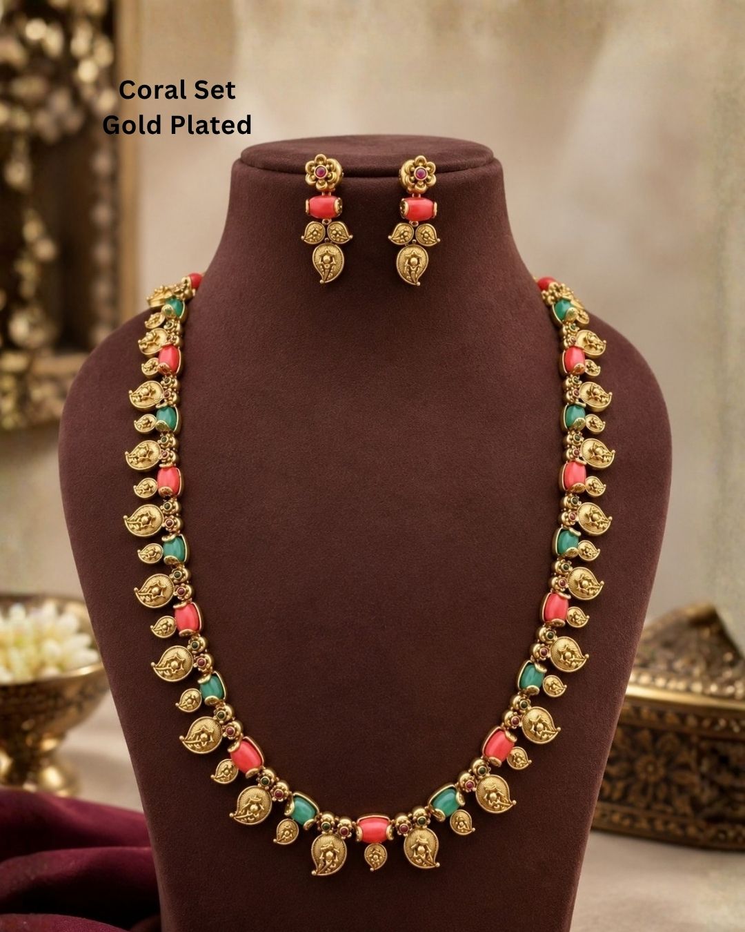Elegant gold plated coral temple jewellery set featuring detailed traditional motifs, coral-colored and green stone embellishments, and matching earrings, perfect for festive and ethnic wear.