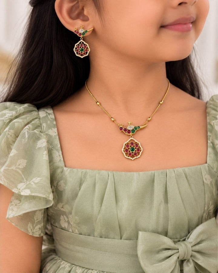 Premium gold plated jewelry set featuring a delicate chain necklace with a floral-inspired central pendant embellished with ruby-colored and green stones, paired with matching drop earrings. Perfect for traditional wear, weddings, festive occasions, parties, and gifting.