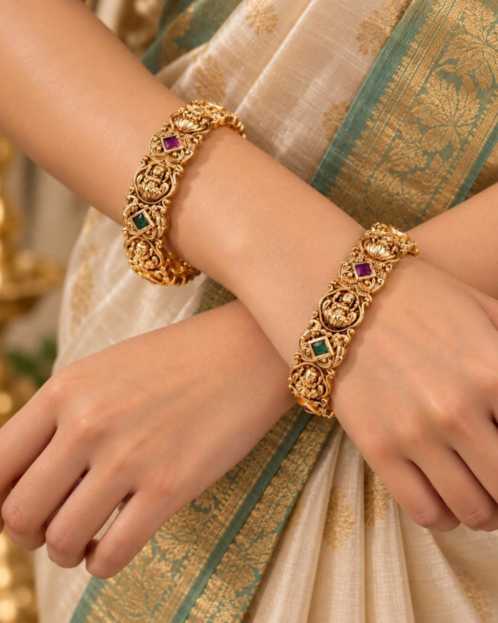 Traditional gold plated temple bangles with Goddess Lakshmi motifs, ruby pink and green square stones, and ornate antique-style craftsmanship.