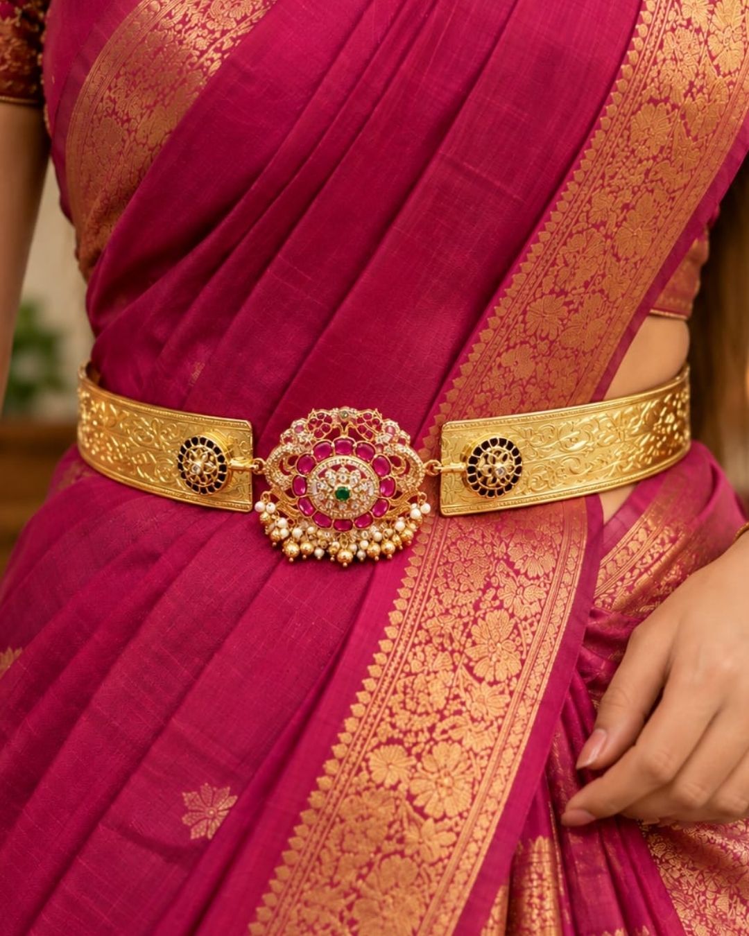Traditional gold plated women’s hip belt with an intricately detailed floral centerpiece, colorful stones, sparkling accents, and pearl drops, perfect for festive and ethnic occasions.