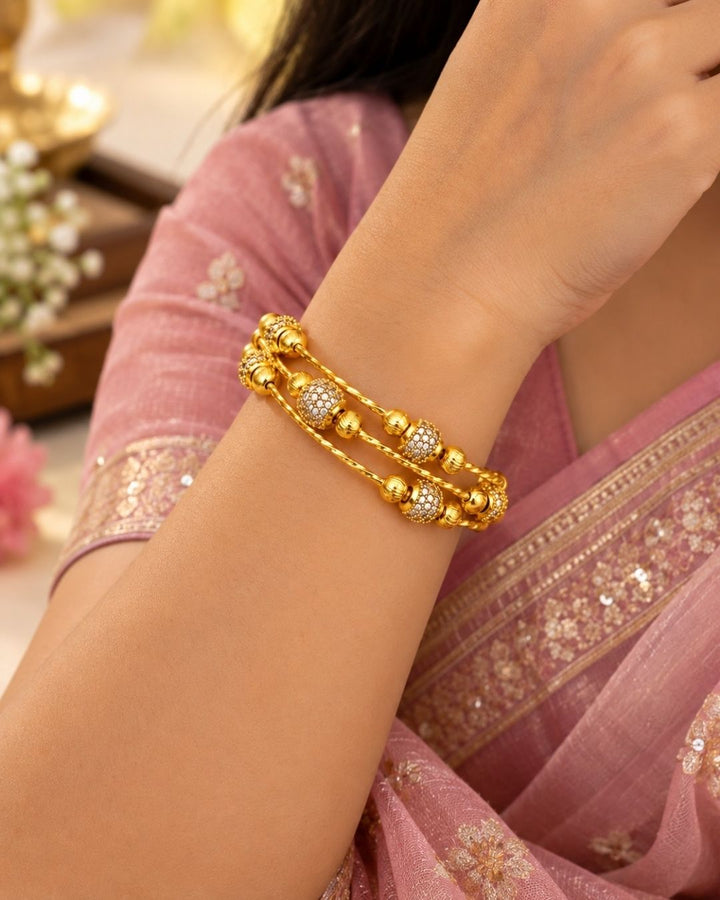 Gold plated adjustable kada for women featuring a triple twisted design, decorative gold beads, and sparkling white stone embellishments.
