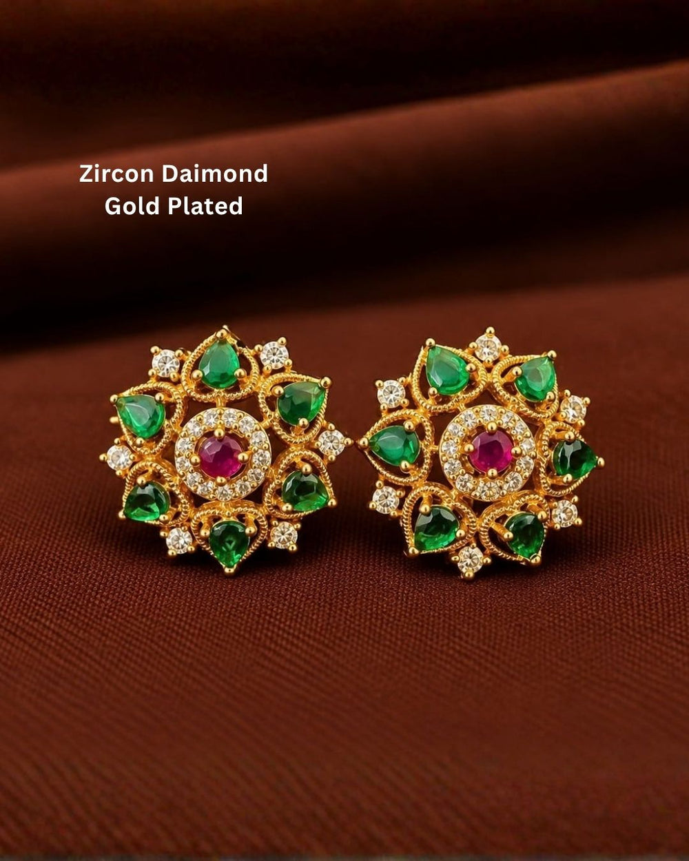 Designer gold plated floral earrings featuring multiple green stones, a ruby-colored center stone, and sparkling zircon accents, perfect for festive and traditional wear.
