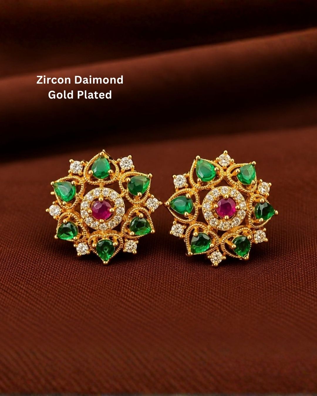Designer gold plated floral earrings featuring multiple green stones, a ruby-colored center stone, and sparkling zircon accents, perfect for festive and traditional wear.