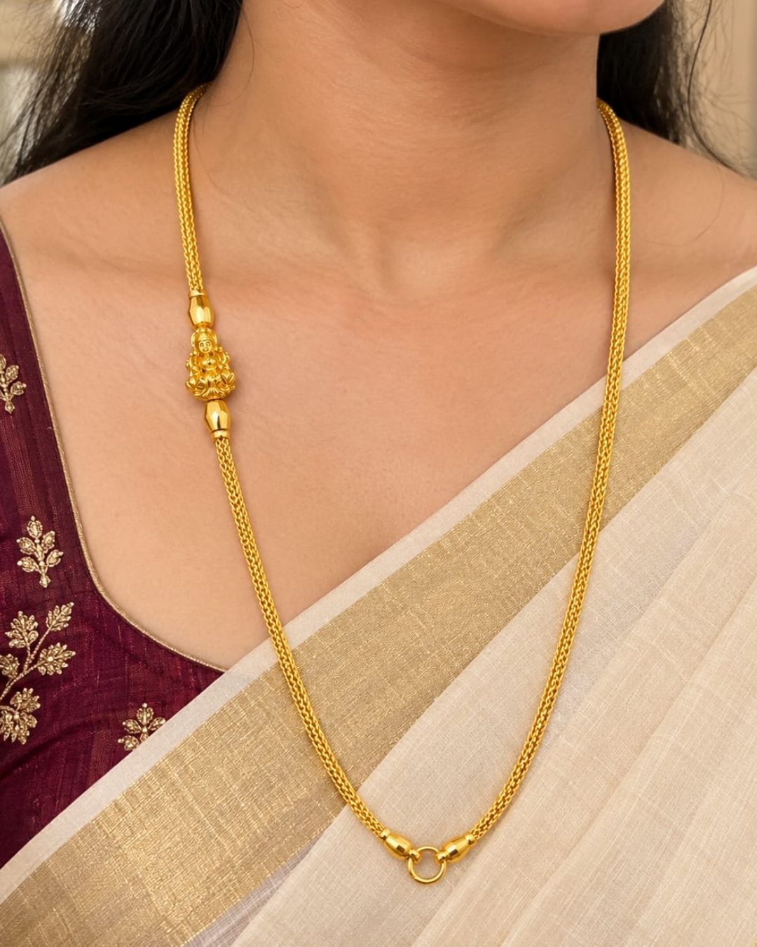 Gold plated thaali chain displayed on a dark wooden surface, highlighting its delicate links and traditional Lakshmi Devi design.