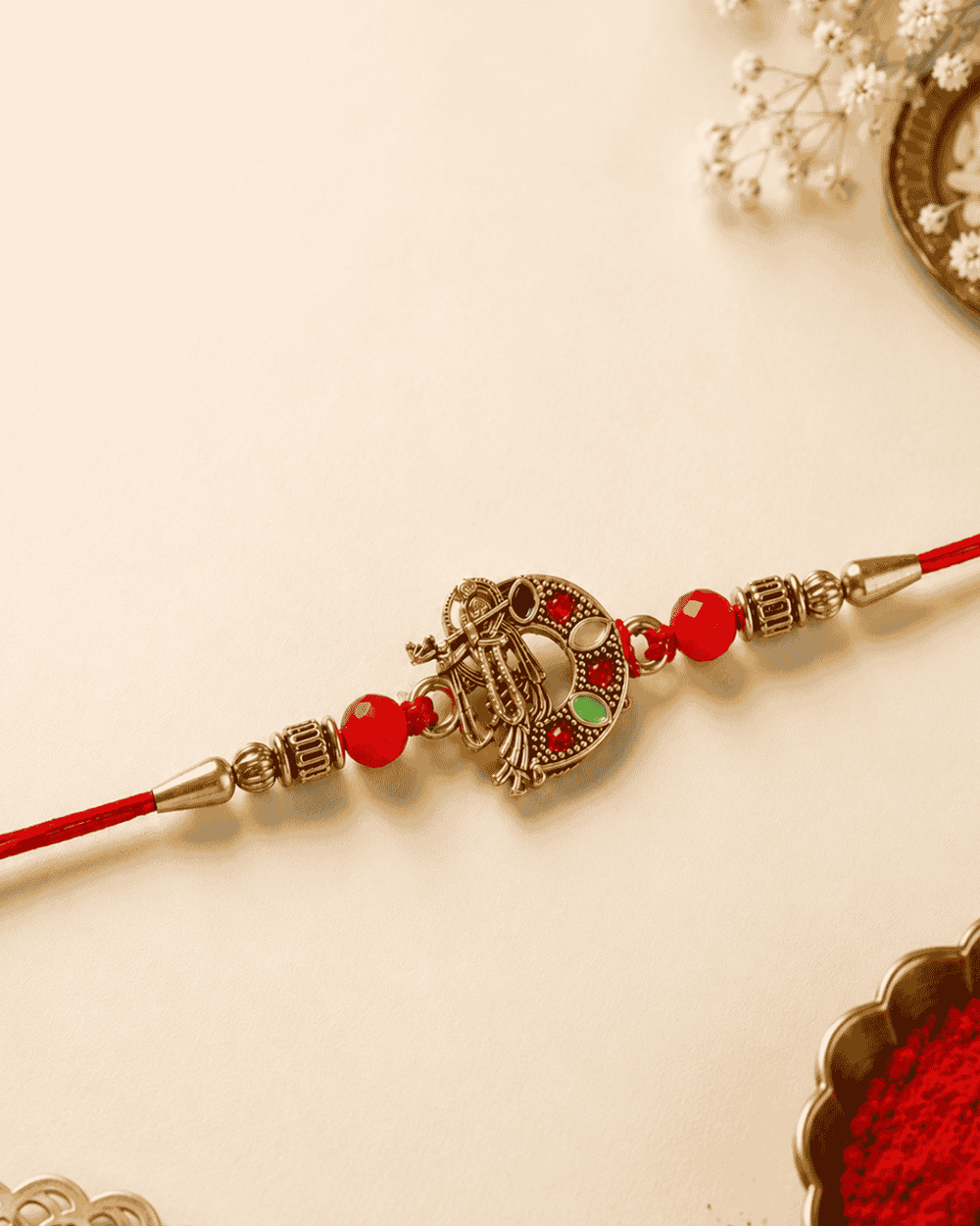 Beautiful gold plated Krishna Rakhi featuring a divine Lord Krishna design with flute, decorative red beads, and premium craftsmanship. Perfect for Raksha Bandhan gifting.