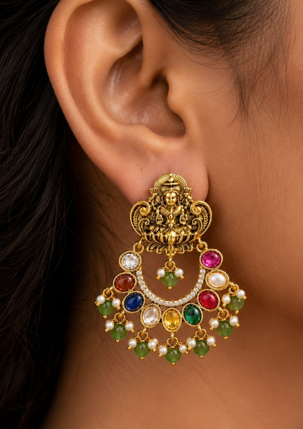 South Indian woman styling Lakshmi gold plated chandbali stud earrings embellished with colorful navaratna stones, pearl clusters and green bead danglers. The intricate temple-inspired craftsmanship and antique finish beautifully complement silk sarees, bridal attire, half sarees and festive ethnic outfits.