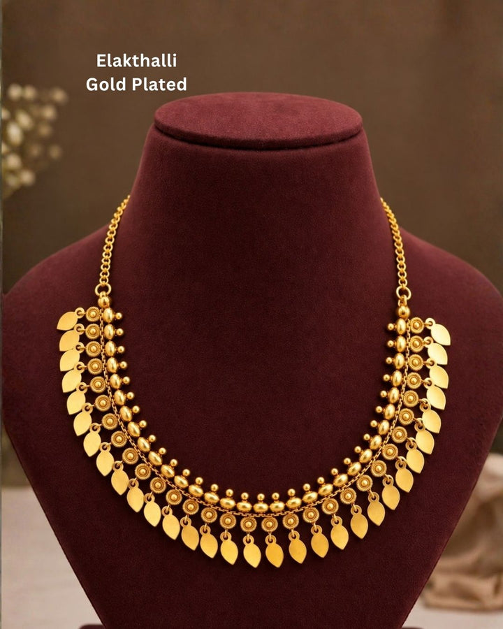 Elegant gold plated traditional necklace featuring multiple leaf-shaped charms, circular textured motifs, and beaded detailing, perfect for festive and traditional wear.
