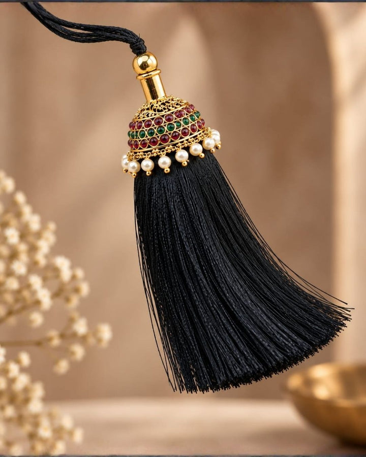 Elegant gold plated Jada Gantalu featuring a dome-shaped design with ruby and green stones, delicate pearl drops, and a long black thread tassel, perfect for bridal and festive hairstyles.
