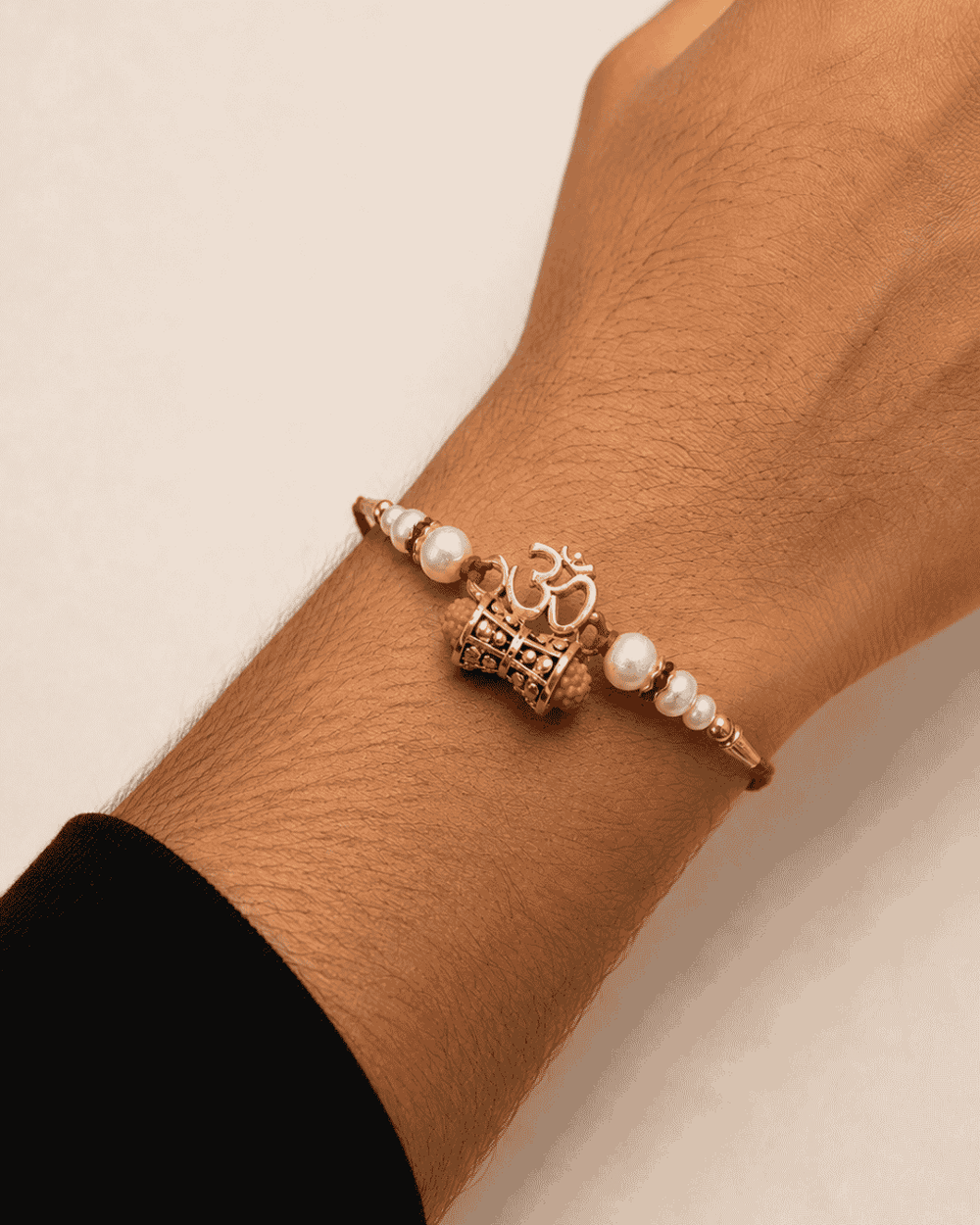 Traditional Om Swastik Rakhi with a beautifully detailed spiritual centerpiece, pearl embellishments, and premium red thread for Raksha Bandhan.