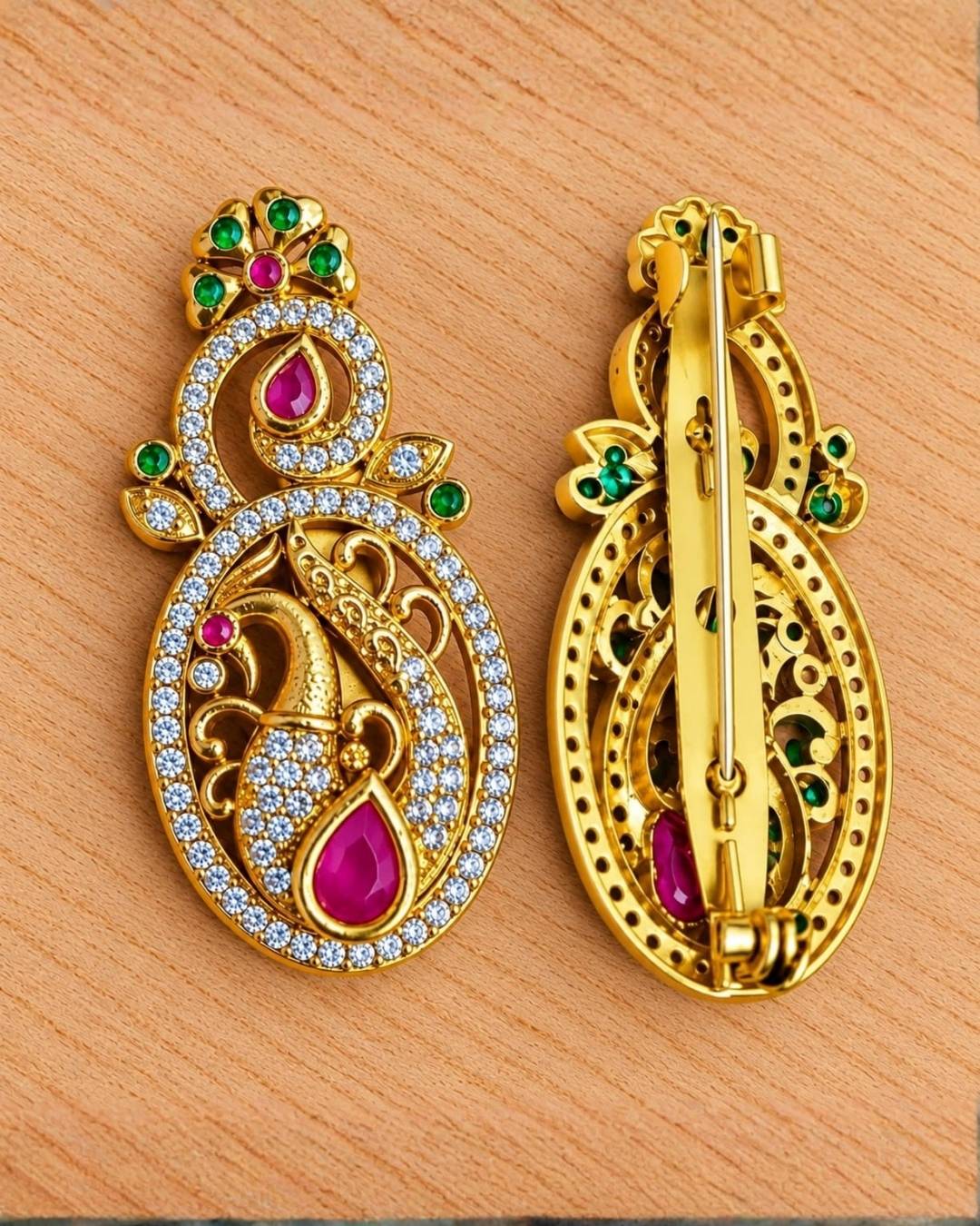Traditional gold finish peacock brooch with intricate feather detailing, crystal embellishments, and vibrant pink and green stones.
