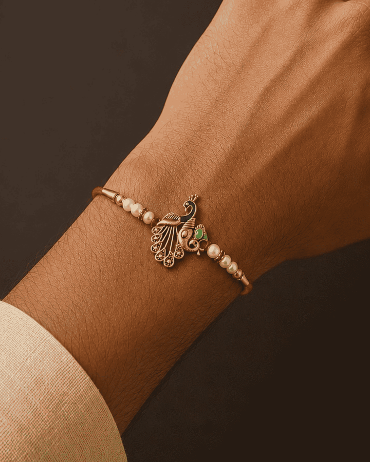 Beautiful Peacock Beads gold plated Rakhi featuring pearl beads, colorful peacock detailing, and an elegant handcrafted design. Perfect for Raksha Bandhan celebrations and thoughtful gifting.