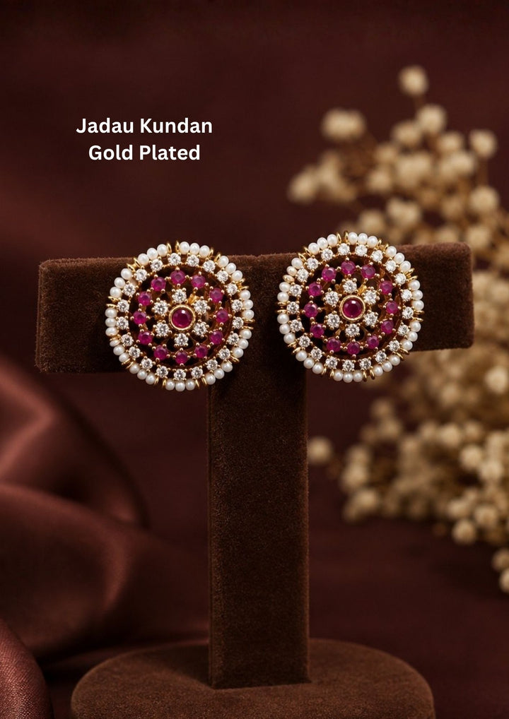 Elegant Jadau Kundan gold-plated stud earrings styled with traditional floral cluster patterns, with Ruby Pink stone settings, and a pearl halo. Perfect for festive celebrations, weddings, ethnic wear, and luxury gifting.
