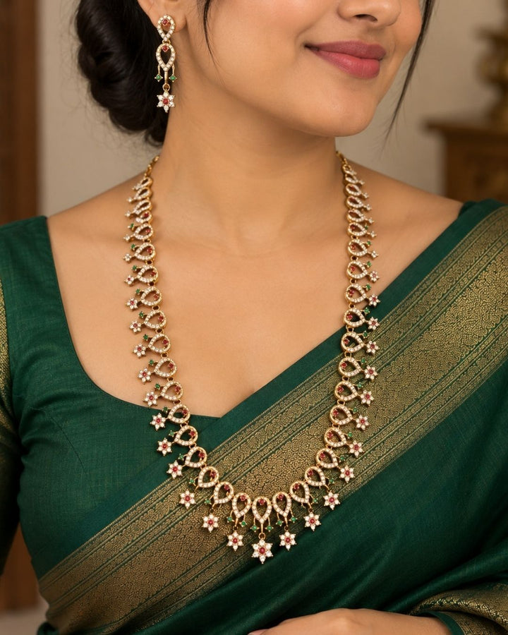 Traditional gold plated necklace set for women featuring ruby-red and emerald-green stones, sparkling accents, intricate teardrop patterns, and matching earrings, perfect for festive and ethnic wear.