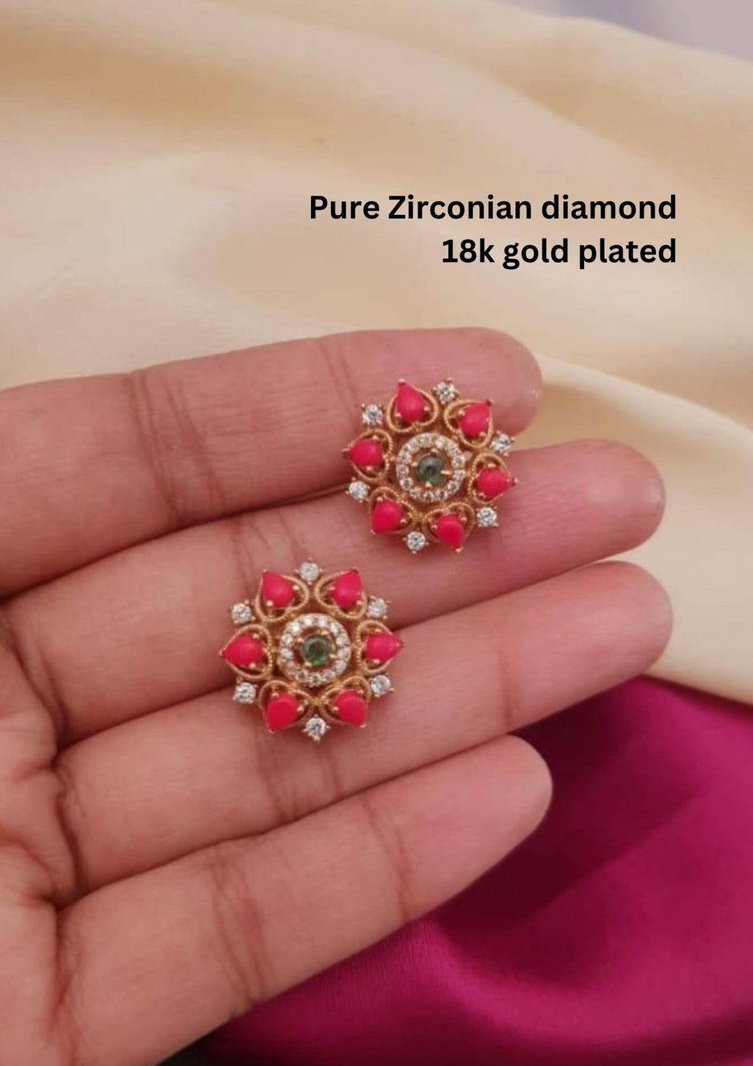 Designer gold plated floral earrings featuring multiple green stones, a ruby-colored center stone, and sparkling zircon accents, perfect for festive and traditional wear.