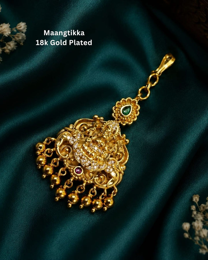 Beautiful traditional gold plated temple pendant featuring an intricate divine motif, ornate filigree detailing, sparkling white stone accents, a green stone accent at the top, and multiple dangling gold bead drops. Perfect for festive occasions, temple visits, traditional outfits, weddings, and spiritual gifting.