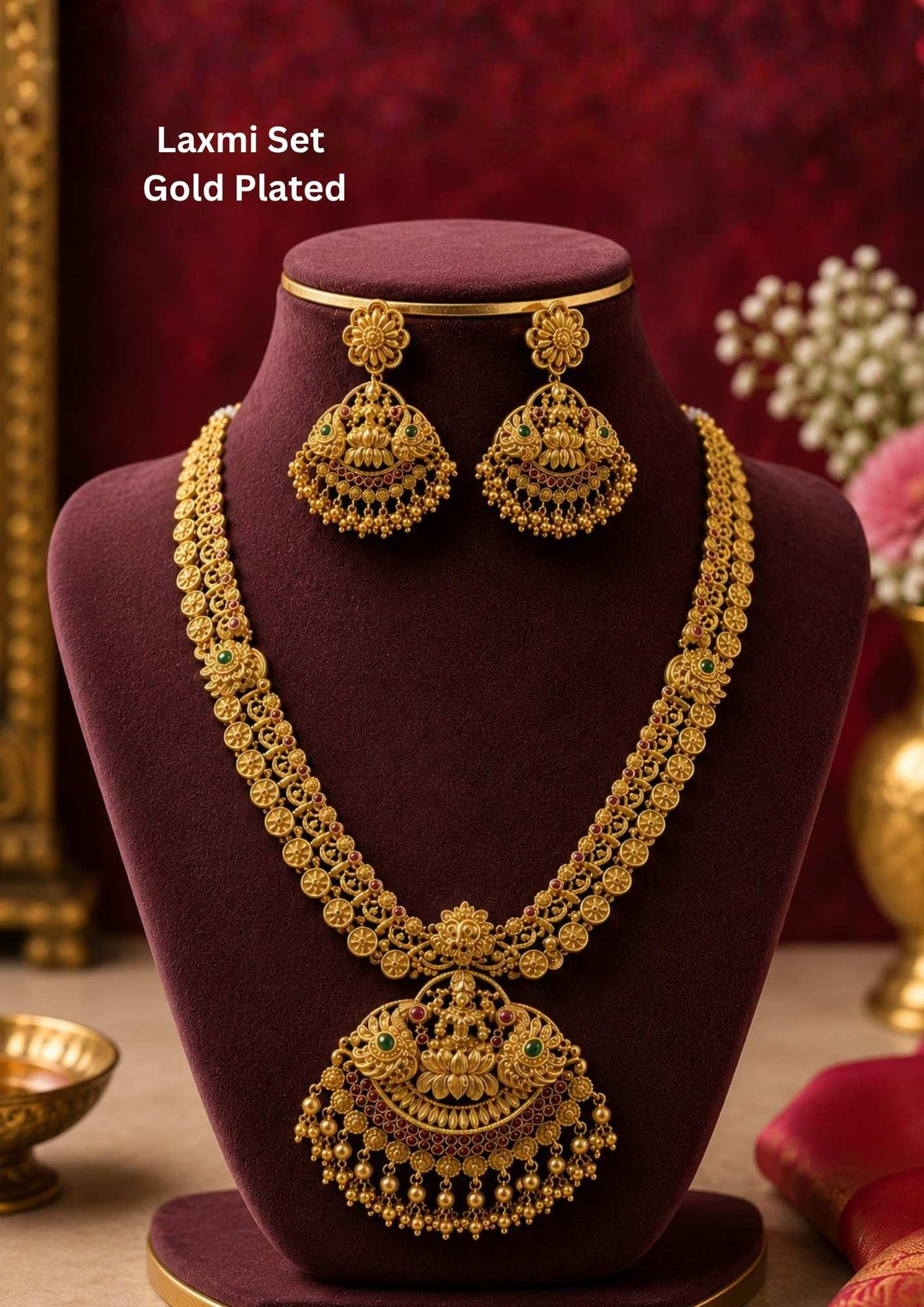 Beautiful gold plated temple necklace featuring an intricately carved Goddess Lakshmi pendant with traditional antique detailing, green and ruby stone accents and matching temple earrings. Ideal for weddings, bridal wear, festivals and traditional occasions.