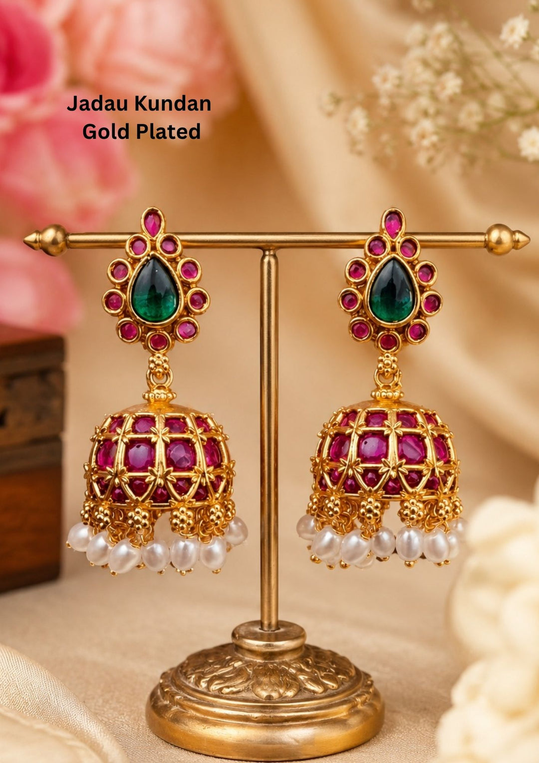 Jadau Kundan gold-plated kada bangles featured in highlighting intricate traditional motifs. The design showcases detailed floral patterns inset with ruby-pink and emerald-green stones, and delicate white Kundan accents running along an antique gold-finished frame.