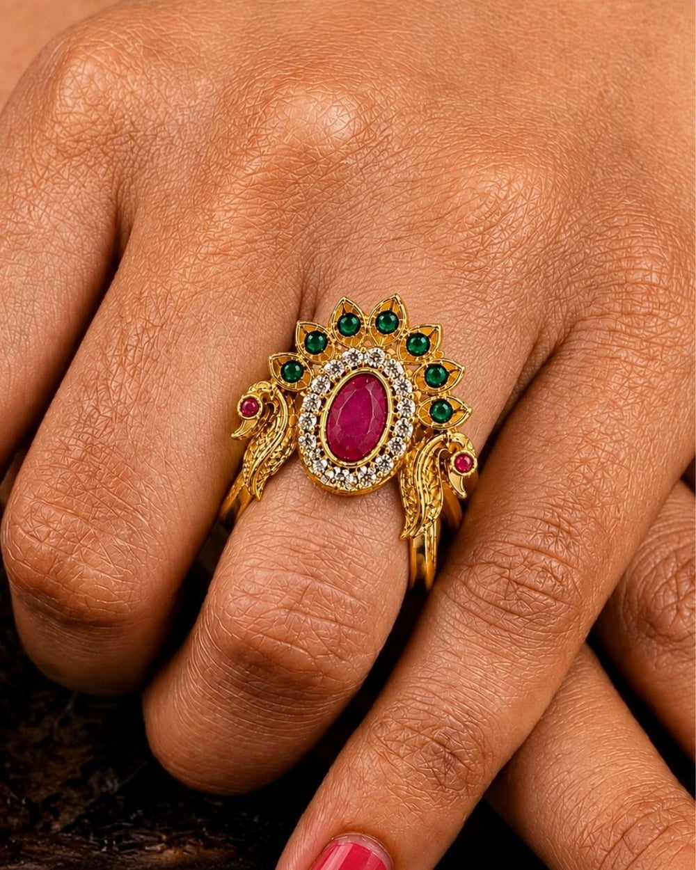 Beautiful peacock design gold plated ring featuring a prominent ruby-colored center stone, surrounding green stones, and sparkling accents. Perfect for festive occasions, traditional outfits, parties, and gifting.