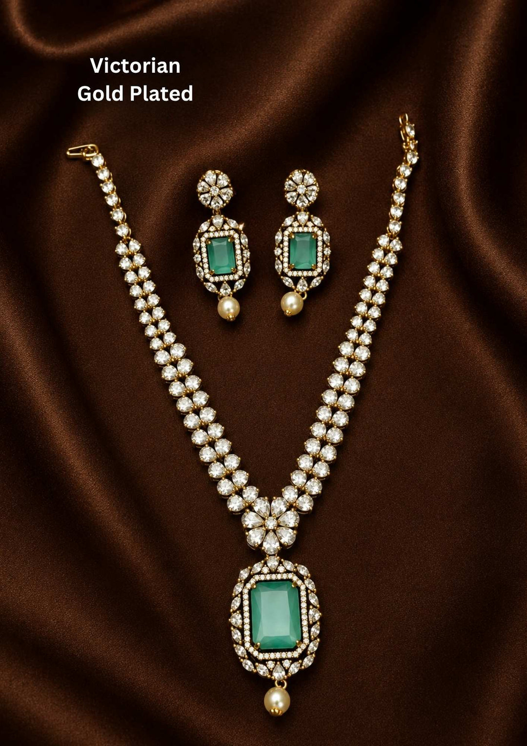 Victorian gold plated jewelry set featuring a dual-strand uncut diamond V-shaped chain, a central floral motif, and a prominent rectangular mint green stone pendant finished with an antique oxidized look and a hanging pearl drop. Includes matching hanging earrings. Perfect for receptions, festive events, and sarees with skin-friendly quality, comfortable fitting
