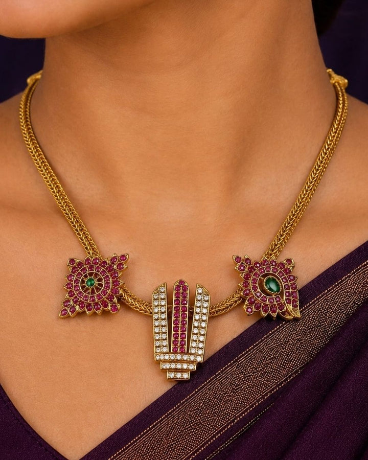 Gold-plated Hamsa hand pendant necklace with red and green stones, worn on a model&