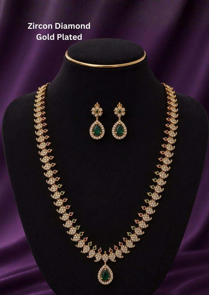 Gold-plated traditional Indian jewelry set featuring a necklace and matching earrings with green teardrop-shaped stones and clear stones Premium gold plated long haram featuring sparkling zircon stones with ruby and emerald accents, paired with matching earrings.