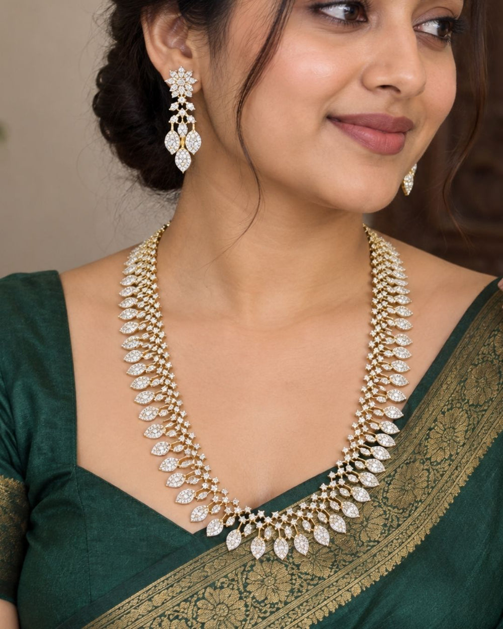 Designer gold plated long necklace and matching earrings featuring intricate leaf motifs embellished with sparkling white stones, perfect for festive, wedding, and traditional occasions.