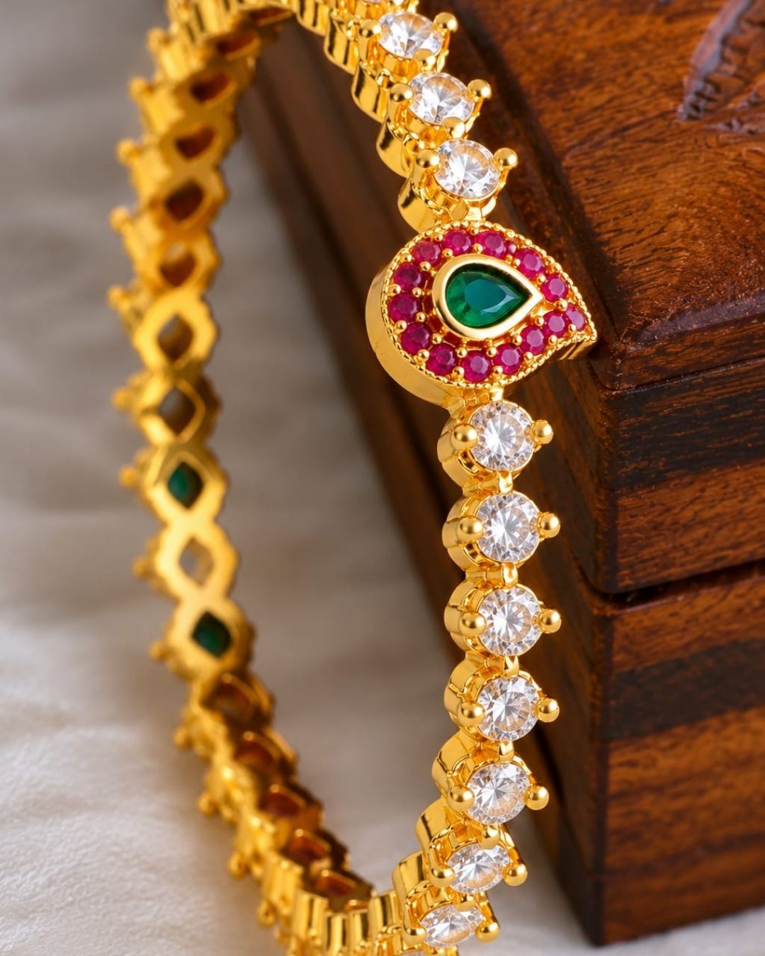 Elegant Jadau Kundan gold plated bangles featuring sparkling kundan stones with emerald teardrop accents. Perfect for weddings and festive occasions.