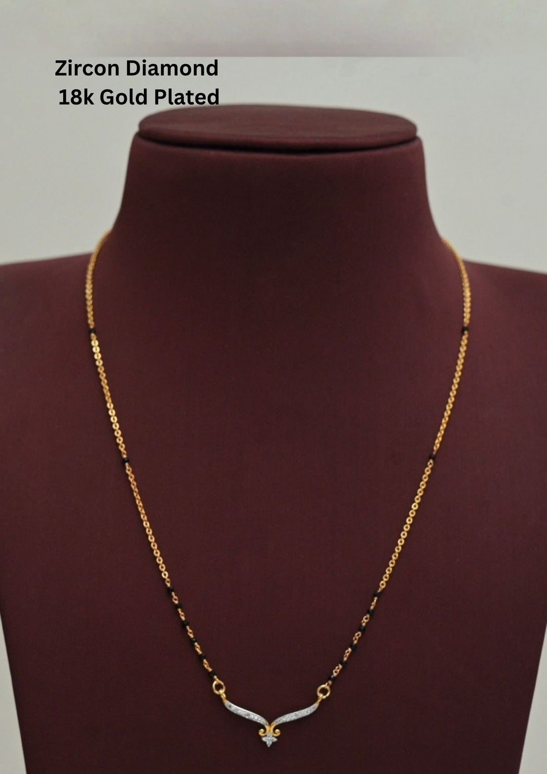 Modern Zircon Diamond gold plated mangalsutra necklace The design features a delicate gold link chain transitioning into sections of traditional small black beads on both sides. The central pendant showcases a sleek, contemporary curved V-shape and a stylized butterfly or floral motif encrusted with sparkling white cubic zirconia stones. This elegant neckpiece perfect for daily wear, office wear, and casual outfits