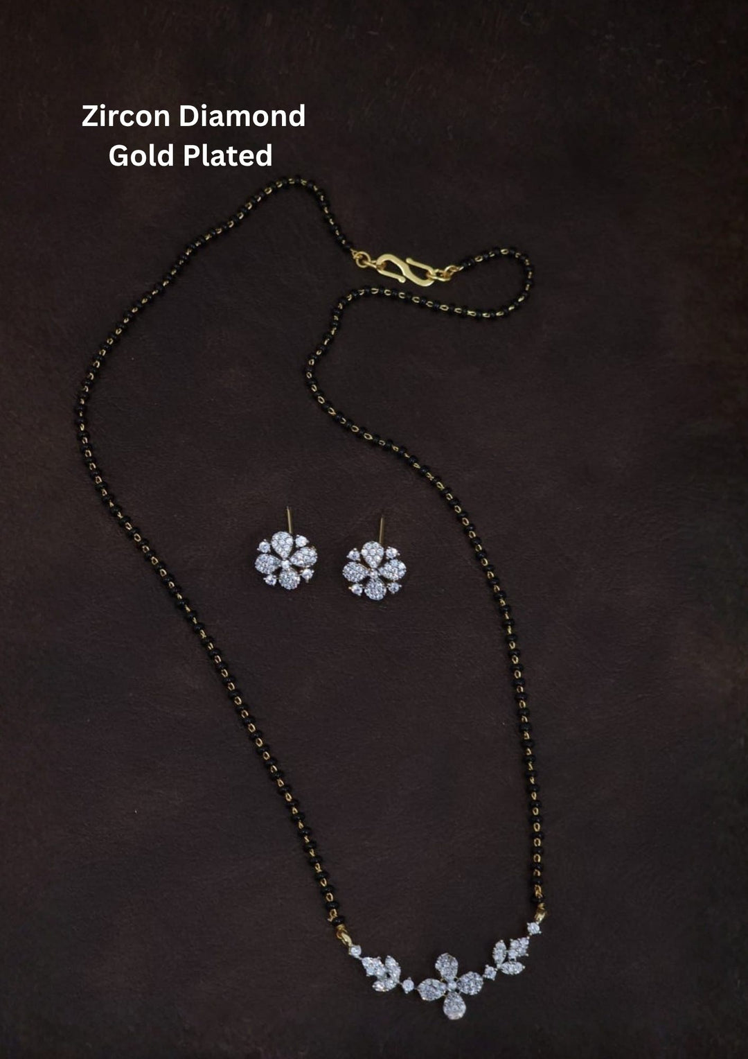 Gold plated black beads mangalsutra featuring an elegant flower pendent and Studs -inspired zircon centerpiece with delicate curved detailing. Lightweight and beautifully crafted for everyday elegance, festive occasions, and gifting.