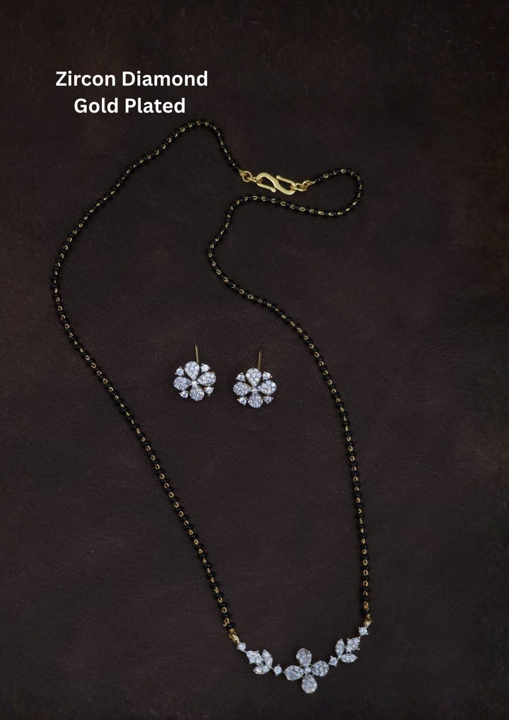 Gold plated black beads mangalsutra featuring an elegant flower pendent and Studs -inspired zircon centerpiece with delicate curved detailing. Lightweight and beautifully crafted for everyday elegance, festive occasions, and gifting.