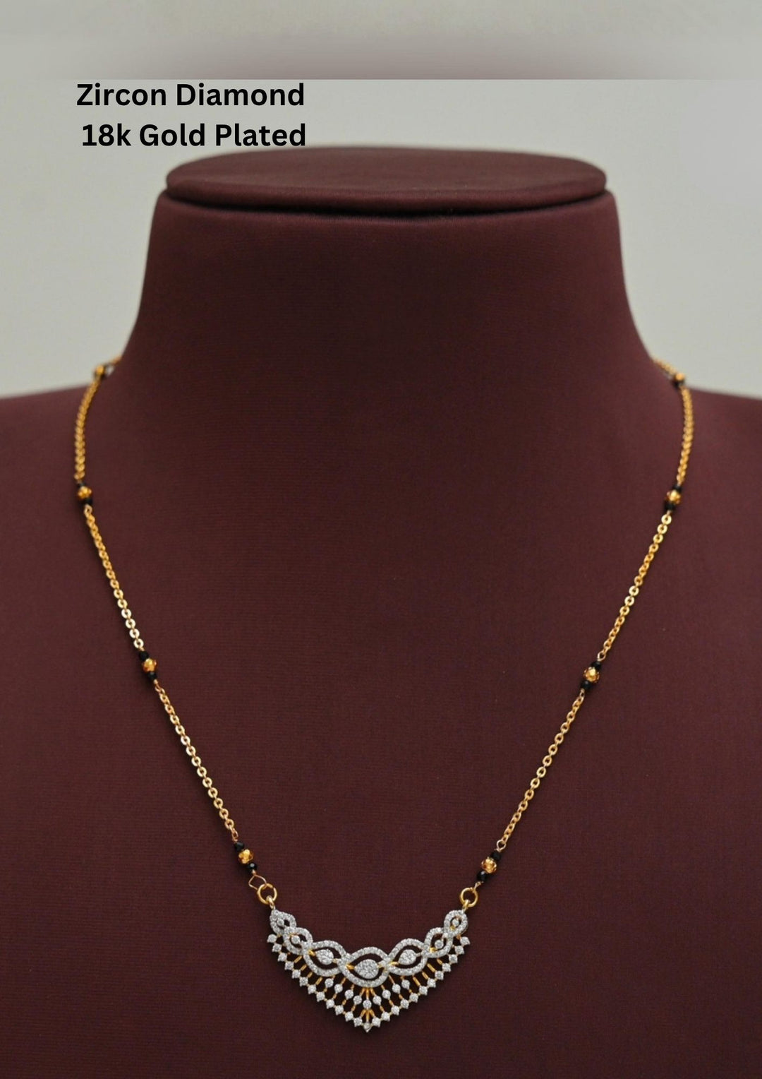 Modern Zircon Diamond gold plated mangalsutra necklace The design features a delicate gold link chain transitioning into sections of traditional small black beads on both sides. The central pendant showcases a sleek, contemporary curved V-shape and a stylized butterfly or floral motif encrusted with sparkling white cubic zirconia stones. This elegant neckpiece perfect for daily wear, office wear, and casual outfits.