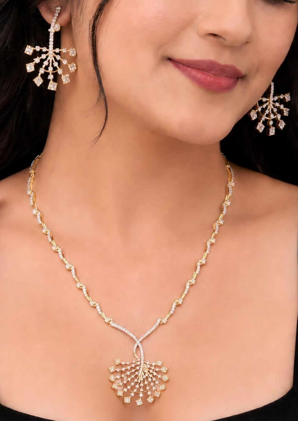 South indian women's Elegant zircon diamond gold plated necklace set featuring a long designer chain with sparkling zircon stone links and a large fan shaped statement pendant decorated with square cut dangling zircon accents. The matching earrings have a stylish geometric floral pattern with shimmering diamond look stones, creating a luxurious modern ethnic appearance suitable for weddings, receptions, parties and festive occasions.