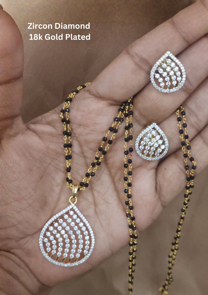 Modern Zircon Diamond gold plated mangalsutra necklace The design features a delicate gold link chain transitioning into sections of traditional small black beads on both sides. The central pendant showcases a sleek, contemporary curved Tear drop pendant with sparkling white cubic zirconia stones. This elegant neckpiece perfect for daily wear, office wear, and casual outfits.
