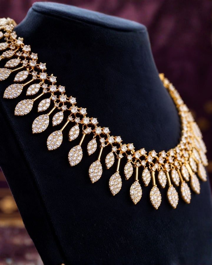 Modern Indian woman styling a zircon diamond gold plated necklace set with matching designer earrings. The jewelry features brilliant diamond-look zircon stones, delicate leaf-shaped danglers and a lightweight elegant finish that beautifully complements sarees, lehengas, gowns and traditional ethnic outfits.