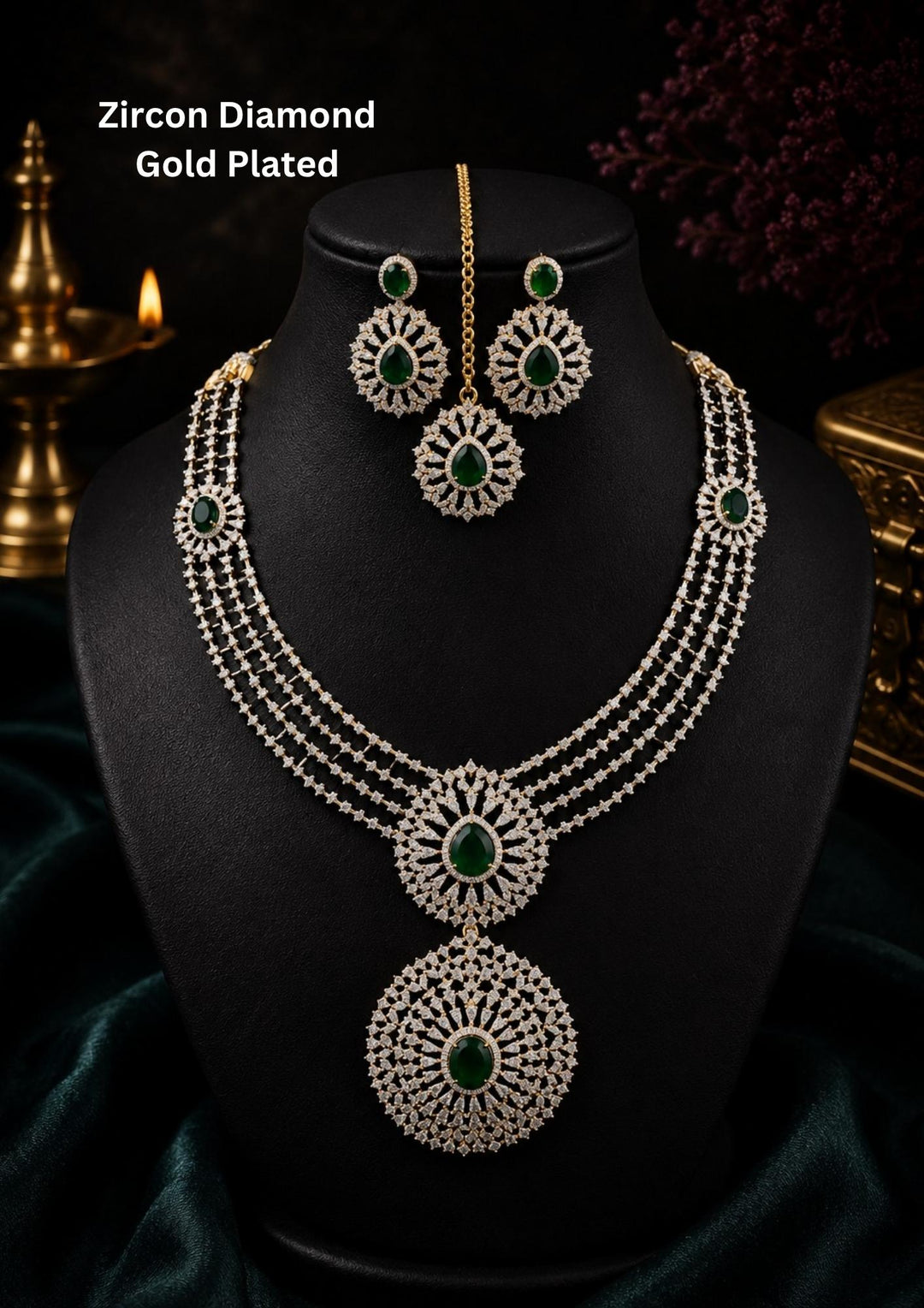Zircon diamond gold-plated necklace and earrings set designed with 3 row zircon diamonds and in the middle it is designed with green emerald stone and it also has matching earrings designed in the leaf pattern with green emerald stud on the top and it also had magtikka perfect for weddings, bridalwear, festivals and its anti fade color