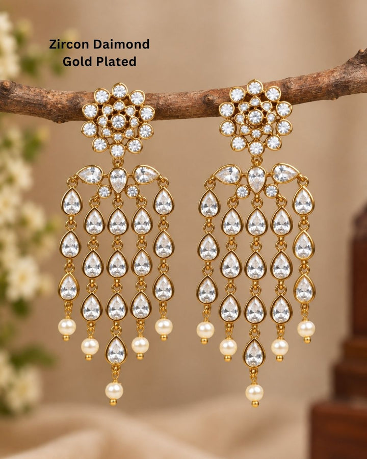  Close up offer south indian women wearing Beautiful zircon diamond gold plated chandelier earrings featuring dazzling pear-shaped zircon stones with graceful pearl drops. Perfect for weddings, receptions, parties, festive occasions, and premium gifting.