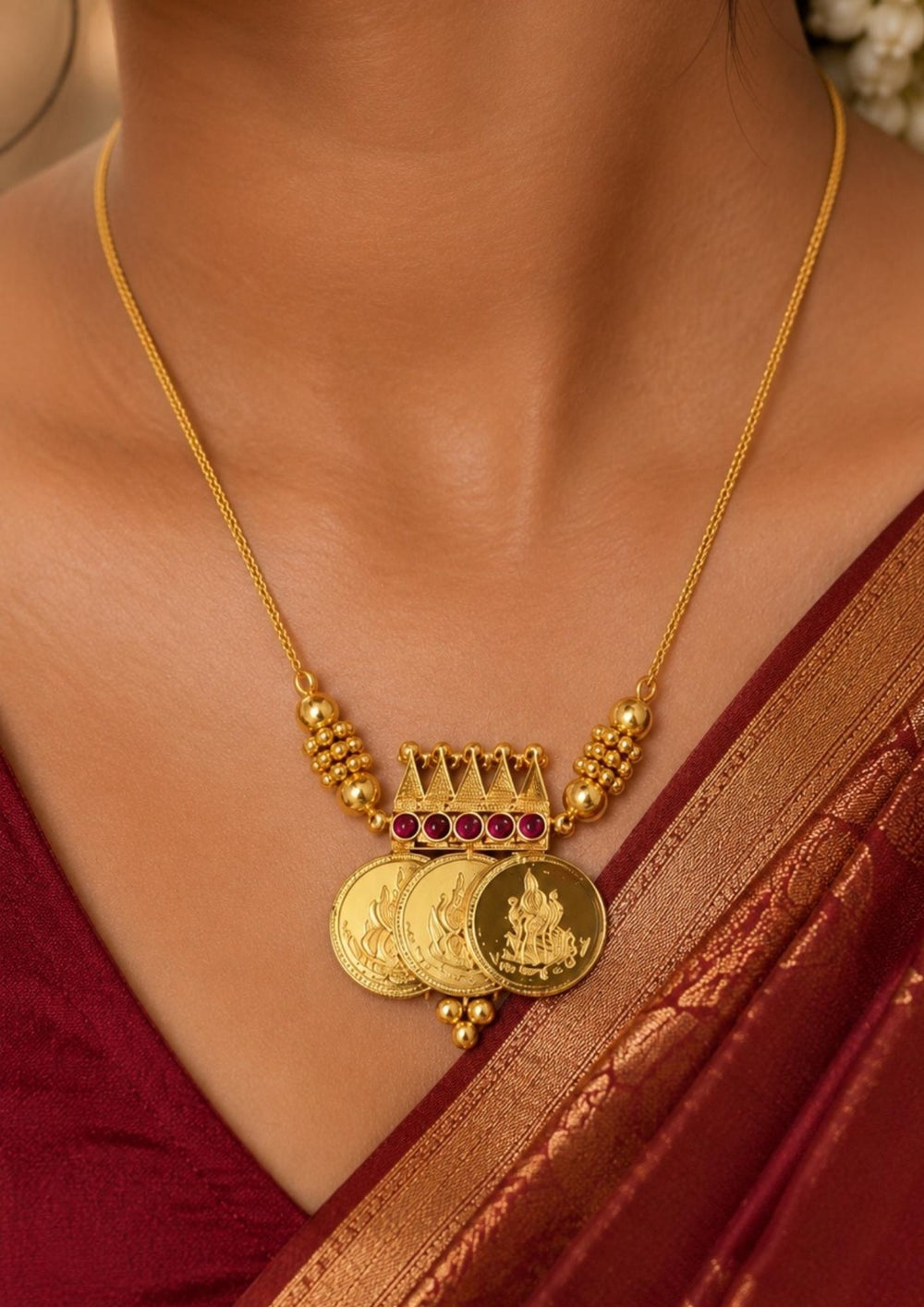 Close up offer south indian women wearing Beautiful gold plated necklace showcasing sacred Lakshmi coin charms and a finely crafted temple-inspired centerpiece.
Designed with elegant ruby stone accents and lightweight construction for comfortable everyday or festive wear.
A perfect traditional jewelry piece to pair with sarees, lehengas, and bridal attire.