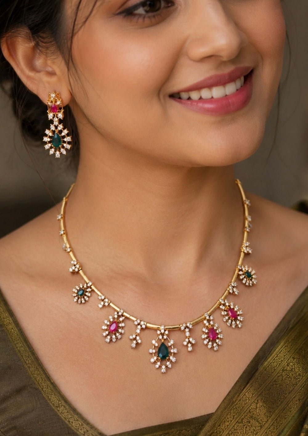 Gold-plated necklace and matching drop earrings features gold-tone settings with clear stones, turquoise blue teardrop stones, and pink round stones. Premium gold plated necklace set crafted with sparkling zircon stones, floral charms, and matching earrings for festive and party wear.
