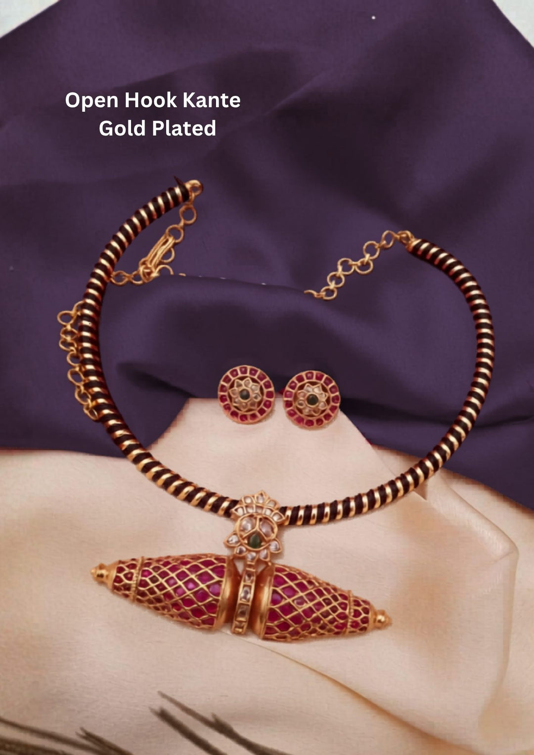 Gold Plated Open Hook Kemp Kante Necklace Set designed with a collar wrapped in a black thread and gold spiral pattern. The central focus is an design of, double-conical spindle pendant decorated with a gold filigree mesh and vibrant red Kemp stones, paired with round matching ear studs. This is a beautiful kante design set