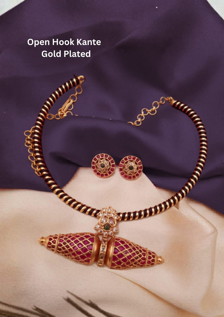 Gold Plated Open Hook Kemp Kante Necklace Set designed with a collar wrapped in a black thread and gold spiral pattern. The central focus is an design of, double-conical spindle pendant decorated with a gold filigree mesh and vibrant red Kemp stones, paired with round matching ear studs. This is a beautiful kante design set
