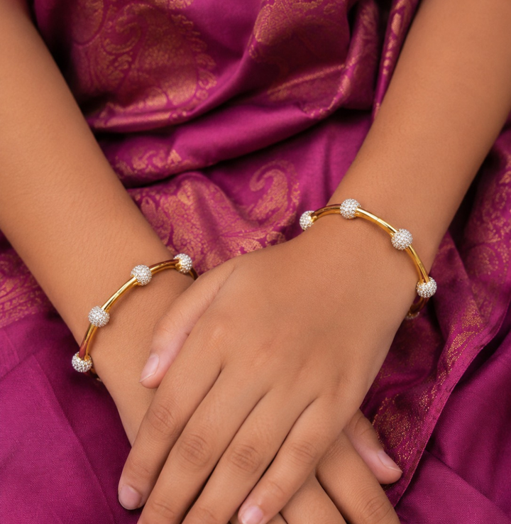 Gold plated bangles with diamond accents on a white background
