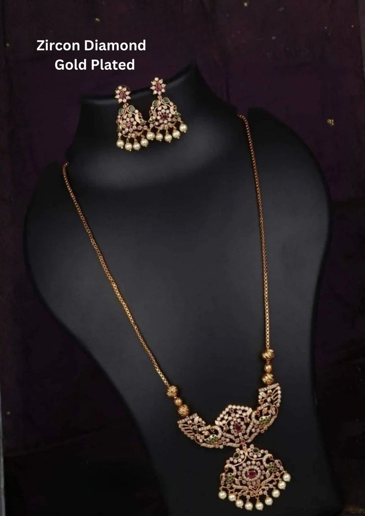 A grand opera-length 18k gold plated haram necklace set showcasing an intricate double-tiered floral medallion pendant. The piece features delicate openwork patterns inlaid with pure Zirconian diamonds, highlighted by pink ruby and green emerald accents and a fringe of seed pearls, complete with matching drop earrings.