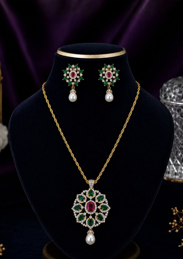 Gold-plated pendant necklace and matching stud earrings displayed on a black velvet jewelry bust. The necklace features a detailed floral pendant with red, green, and blue stones, while the matching earrings are shown above the bust.