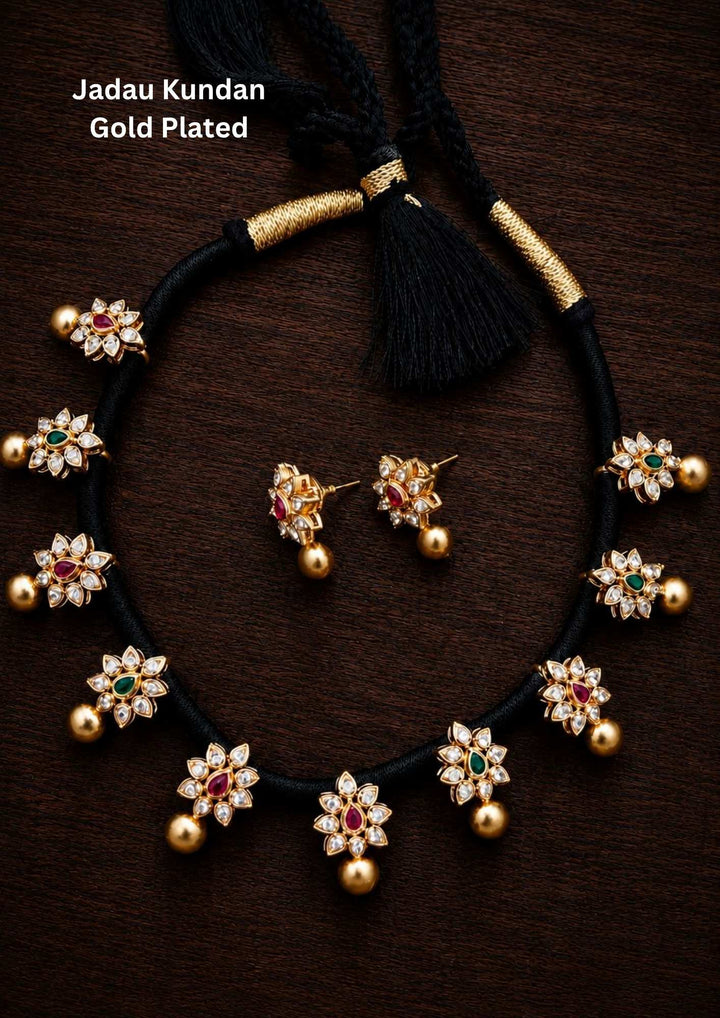 gold plated jadau kundan black thread necklace with matching earrings designed with green and red ruby shape in flower shape designed perfect for occasions and festivals it is anti fade color