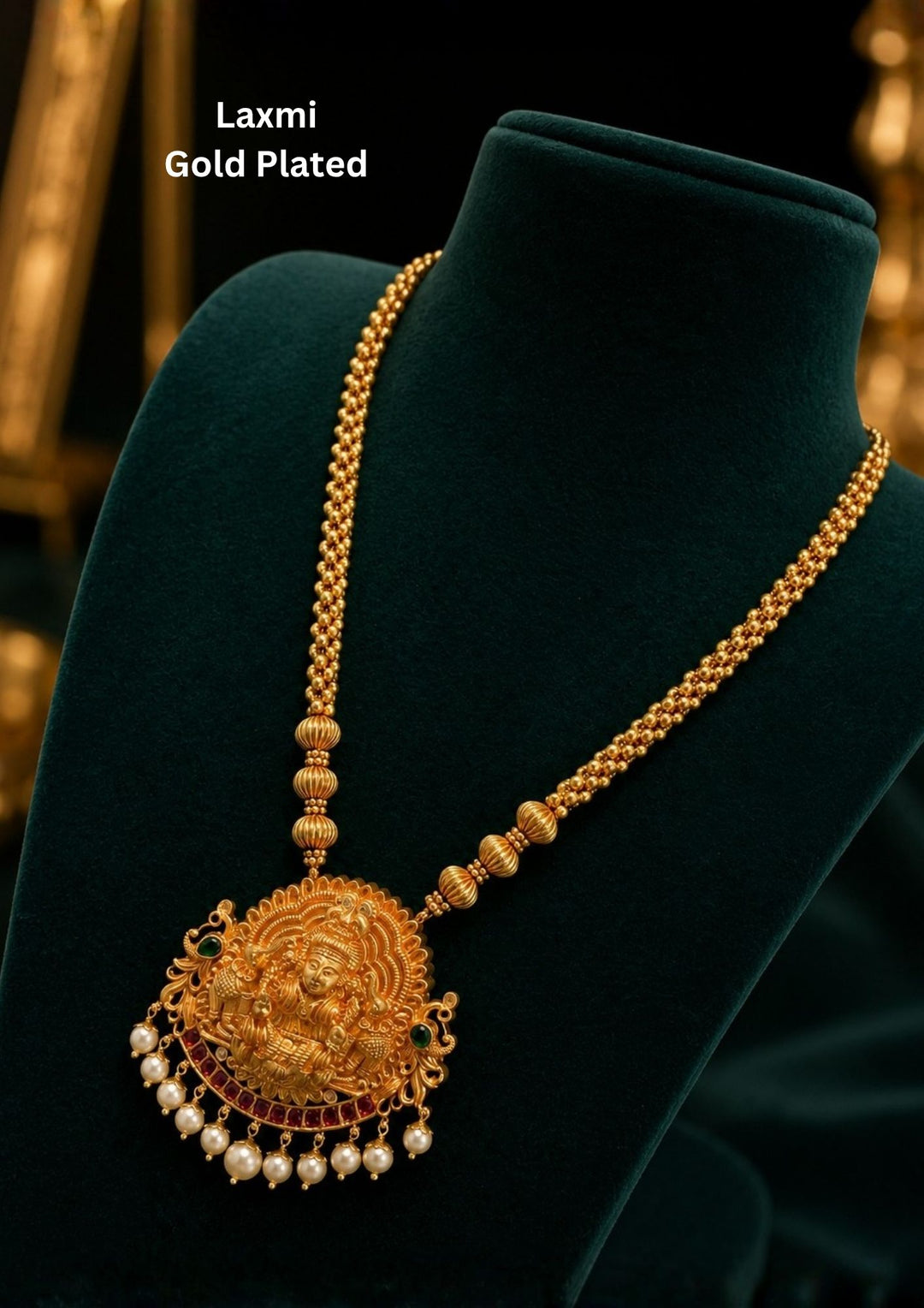 Traditional jadau kundan gold plated haram necklace featuring an intricately crafted Lakshmi Devi pendant with antique detailing, ruby-tone accents and elegant pearl drops. The long beaded chain enhances the temple jewelry look, making it ideal for bridal and festive styling.