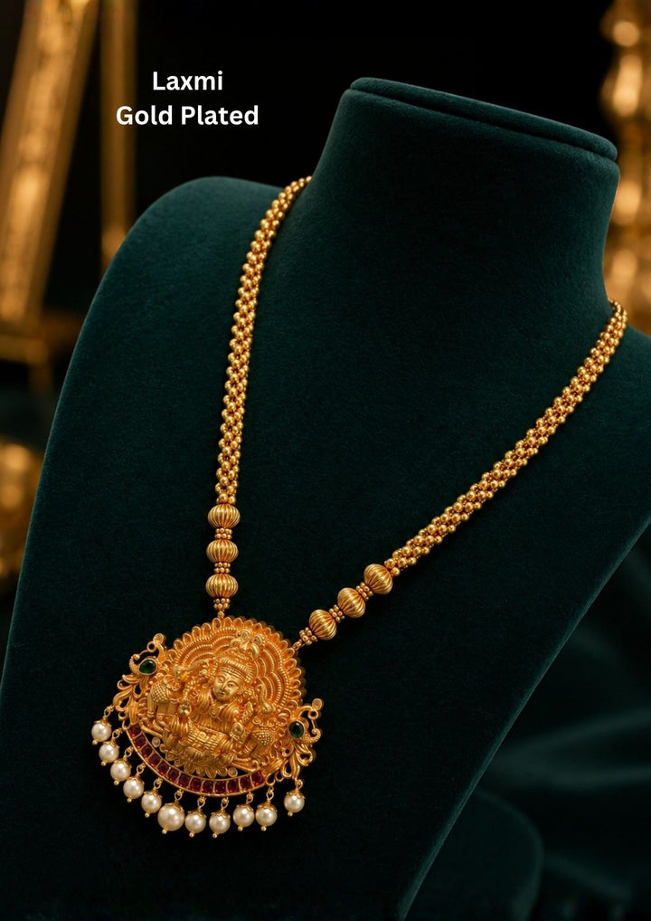 Traditional jadau kundan gold plated haram necklace featuring an intricately crafted Lakshmi Devi pendant with antique detailing, ruby-tone accents and elegant pearl drops. The long beaded chain enhances the temple jewelry look, making it ideal for bridal and festive styling.