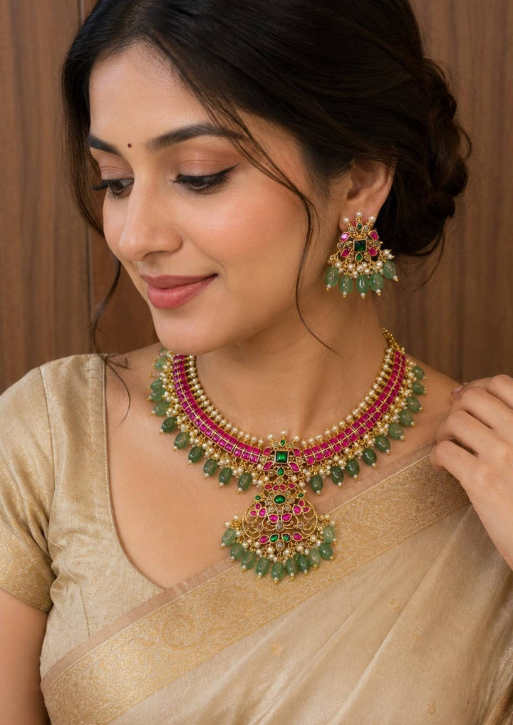 south indian women wearing Jadau Kundan Gold-plated necklace and earrings set with green and red stones  come with beads Kante necklace set for traditional look and can be used for festivals, functions  